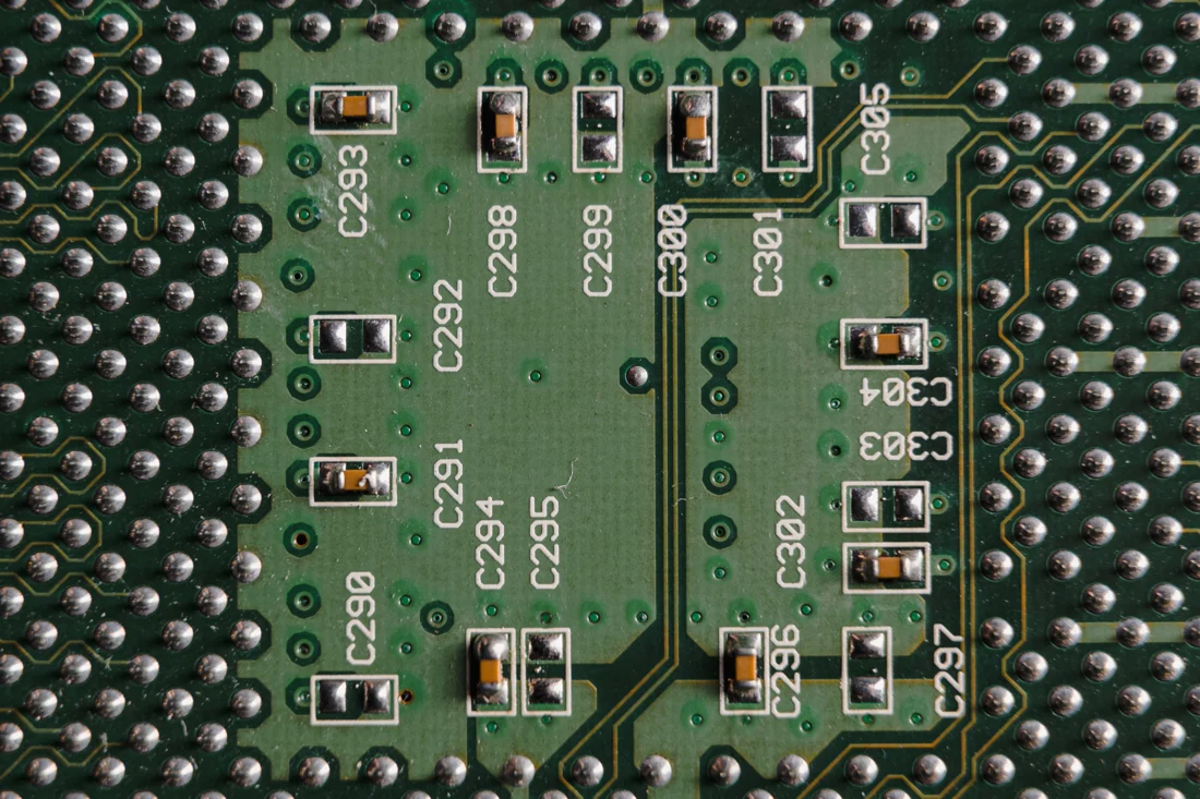 Solder joints, copper traces and small capacitors on a green circuit board